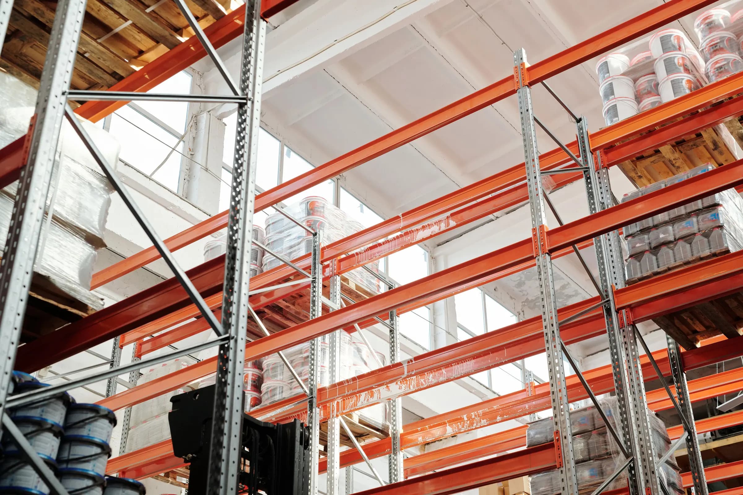 Orange pallet racking in a bright warehouse, seen from below