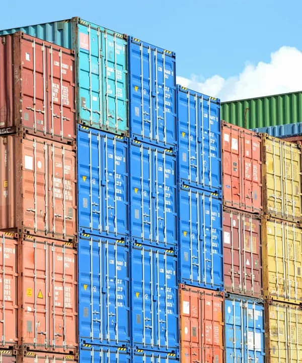 Stacked shipping containers under a blue sky